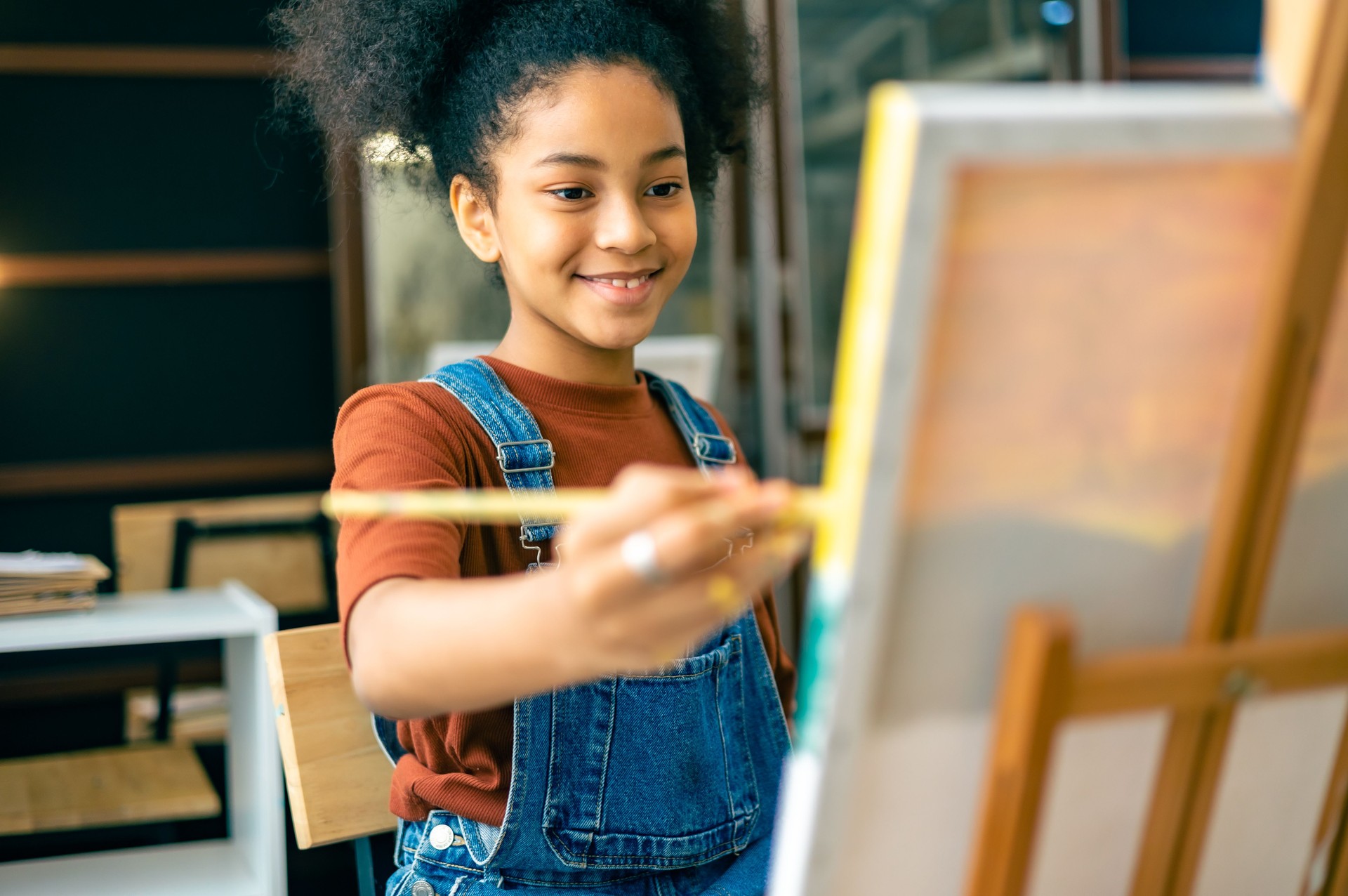 African kids drawing in classroom, young girl happy funny study and play painting acrylic color on canvas.Group of  children drawing with  teacher in school studio.